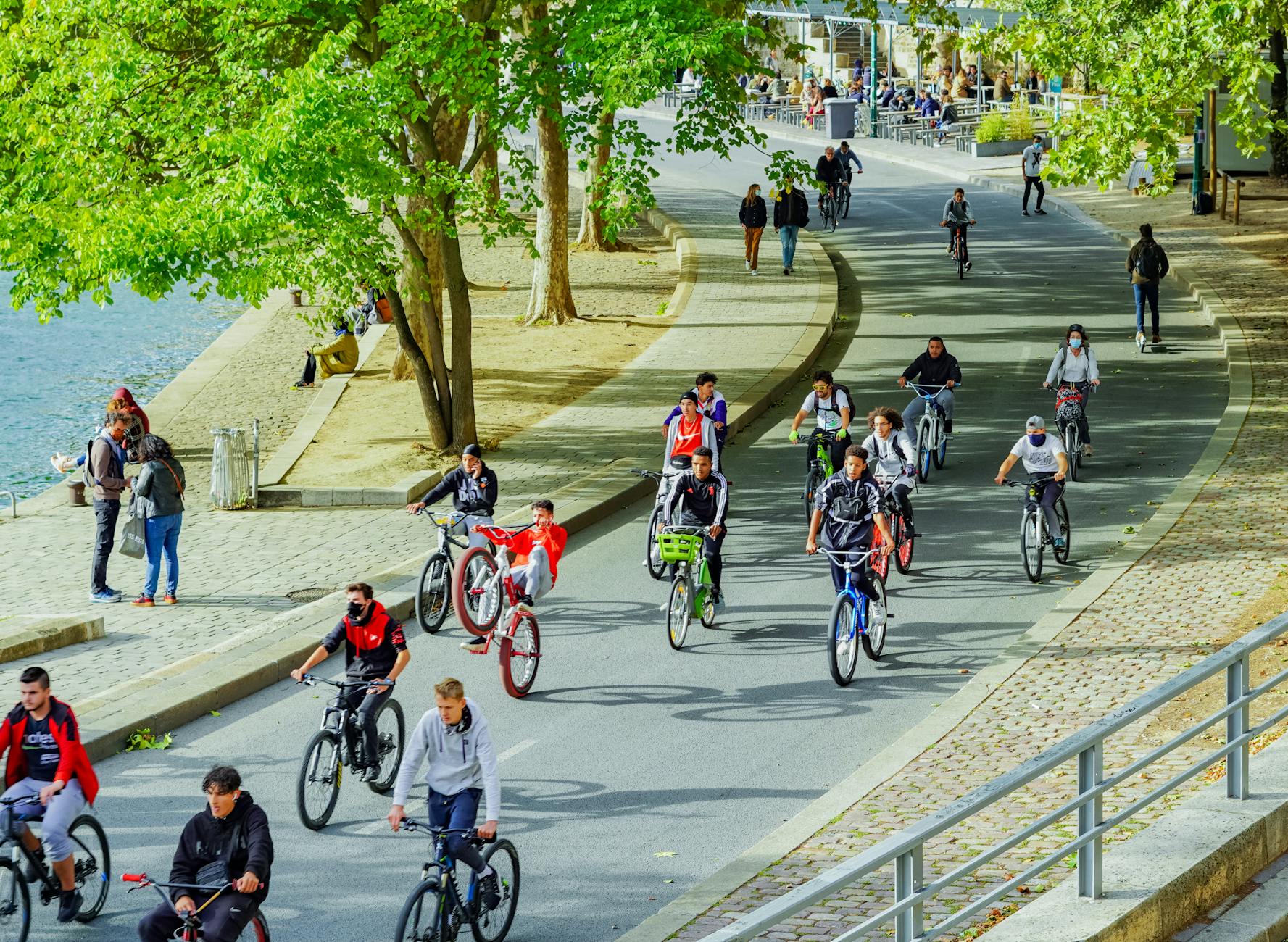 Grupa rowerzystów jedzie ścieżką wzdłuż rzeki w słoneczny dzień