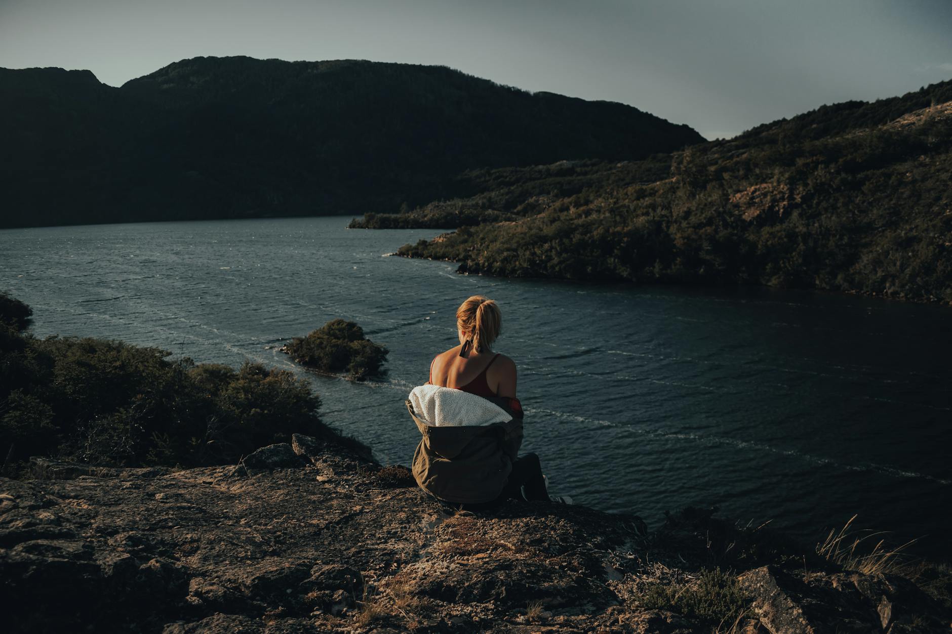 Kobieta siedzi na skarpie z widokiem na spokojną rzekę w Sosnowicy