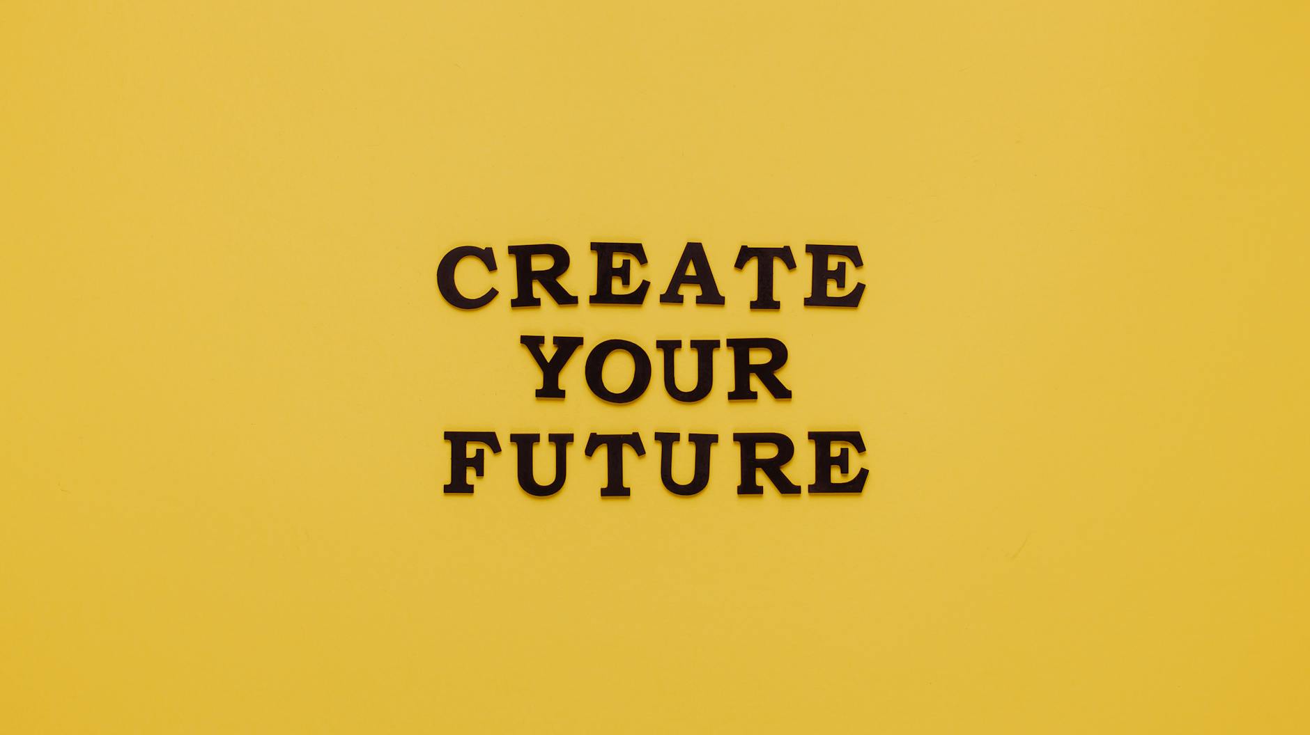 Napis CREATE YOUR FUTURE na żółtym minimalistycznym tle