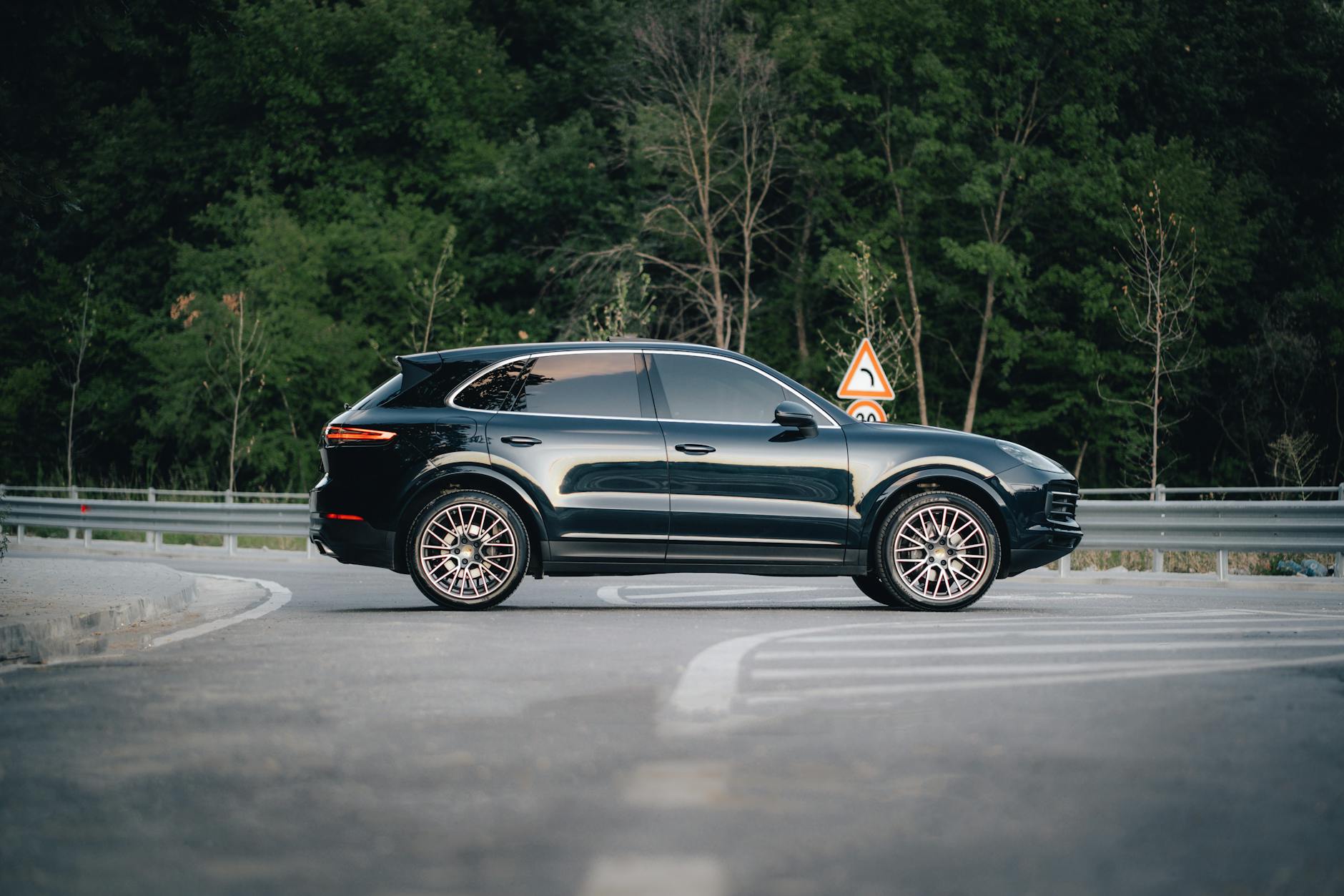 Czarny luksusowy SUV zaparkowany na leśnej, spokojnej drodze